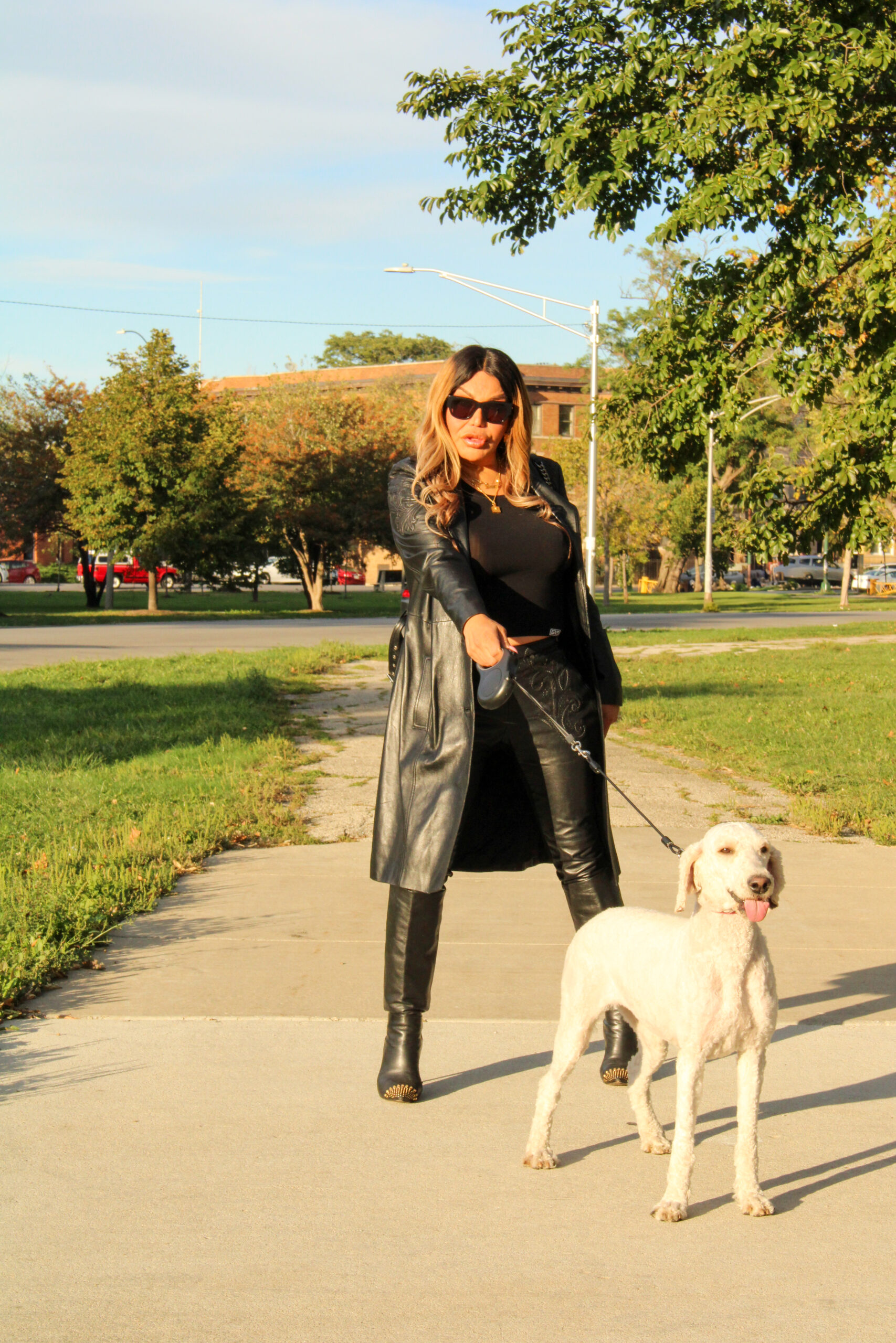 Monica standing in front of a park with a white dog